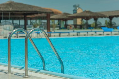 Yazın bir kır otelinde mavi şeffaf suyla dolu bir havuz.