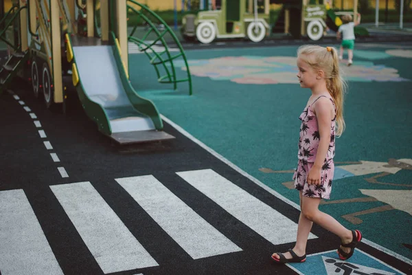 Klein meisje spelen op de speelplaats in de verkeersregels — Stockfoto