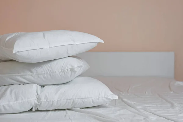 Аккуратная стопка постельных подушек и одеяло лежат на кровати — стоковое фото