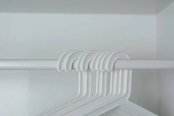 Белые вешалки висят на белом баре в белом шкафу — стоковое фото