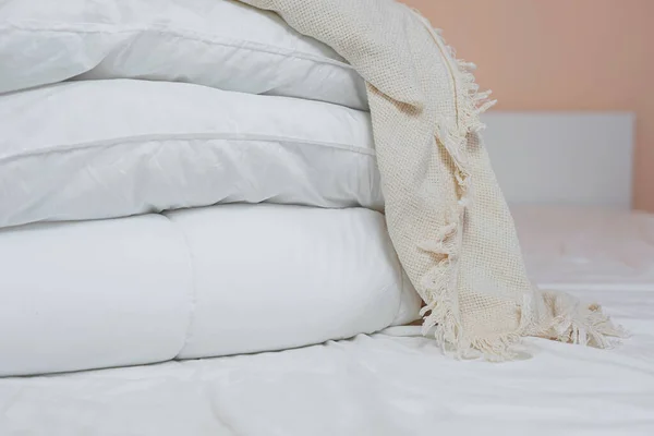 Pile d'oreillers et de couvertures blancs se trouve sur le lit sur un drap blanc sur le dessus, recouvert d'une couverture Photos De Stock Libres De Droits