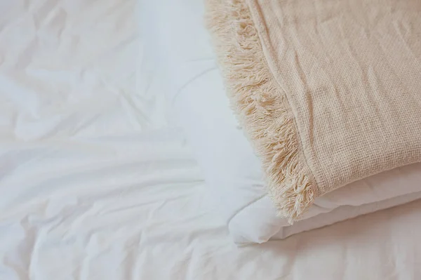 Stapel witte kussens en dekens ligt op het bed op een wit laken bovenop, bedekt met een deken. Afwerken van textiel Stockfoto