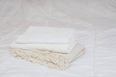 Ev yapımı tekstil. Bir yığın havlu beyaz bir yatakta yatıyor.