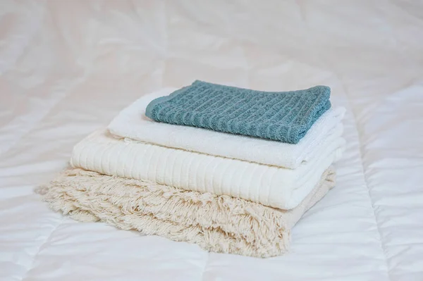 Home textiles. A stack of towels lies on a white bed — Stock Photo, Image