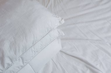 Yatağın üzerinde bir yorgan ve yastık yığını var.