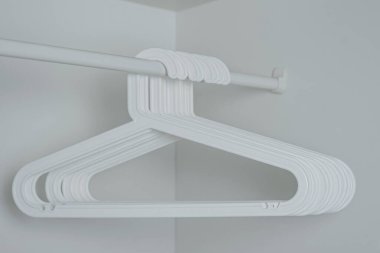 Beyaz askılar beyaz bir dolapta beyaz bir çubuğa asılı.