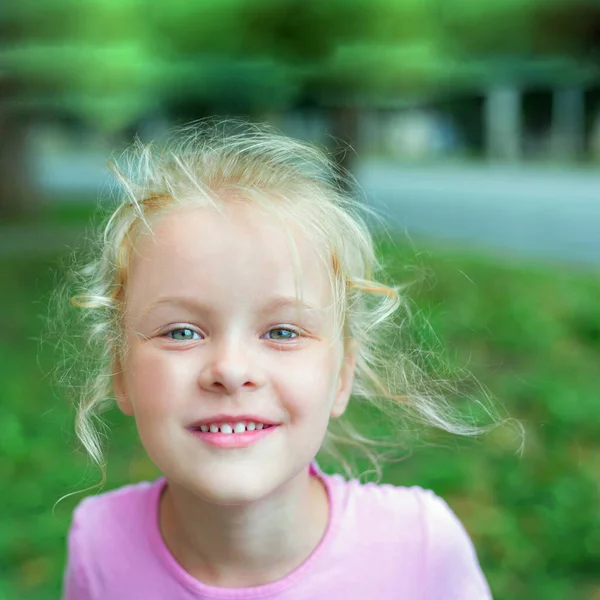 Retrato de cerca de una niña feliz con el pelo rubio. Chica sonriendo a la cámara —  Fotos de Stock