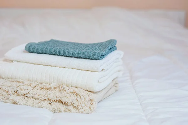 Home textiles. A stack of towels lies on a white bed — Stock Photo, Image