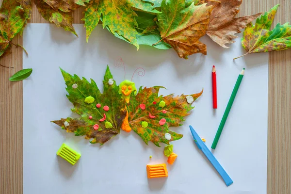 Hoe maak je een herfst ambachtelijke van bladeren en plasticine thuis. Kinderkunstproject. Doe-het-zelf concept. Kinderen handen maken een vlinder op een witte achtergrond. Stap-voor-stap foto-instructies. Stap 6 Stockfoto