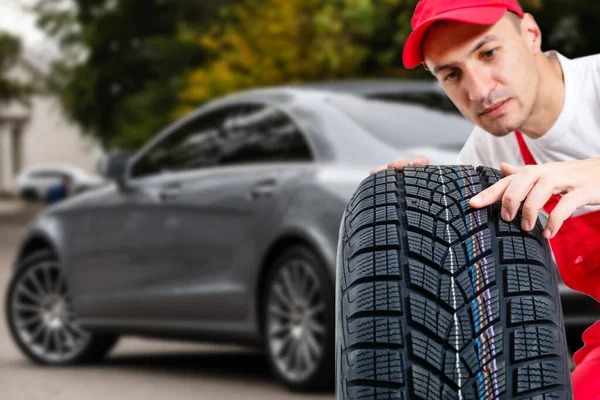 Mechanic holding a tire tire at the repair garage. replacement of winter and summer tires.