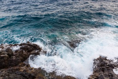 Okyanus dalgaları taşlara çarpıp çarpıyor.