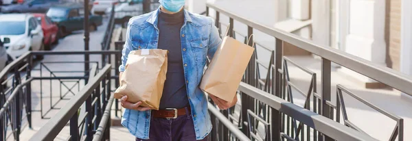 Delivery man holding paper bag with food on white entrance of house background , food delivery man in protective mask