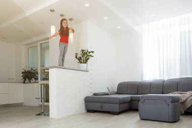 Uzun boylu, küçük bir kız çocuğu evde oynaşıp eğleniyor. Eğlenceli aktiviteler, sportif sağlıklı yaşam tarzı konsepti.