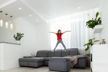 Uzun boylu, küçük bir kız çocuğu evde oynaşıp eğleniyor. Eğlenceli aktiviteler, sportif sağlıklı yaşam tarzı konsepti.