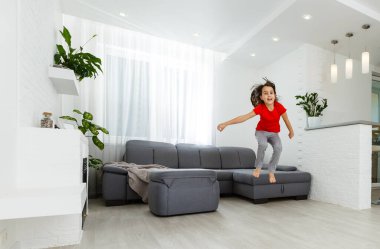 Uzun boylu, küçük bir kız çocuğu evde oynaşıp eğleniyor. Eğlenceli aktiviteler, sportif sağlıklı yaşam tarzı konsepti.