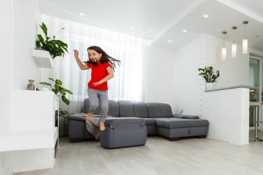 Uzun boylu, küçük bir kız çocuğu evde oynaşıp eğleniyor. Eğlenceli aktiviteler, sportif sağlıklı yaşam tarzı konsepti.