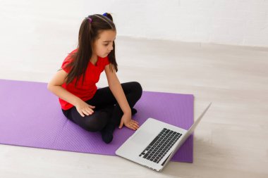 Gülümseyen küçük kız evde egzersiz yapıyor.