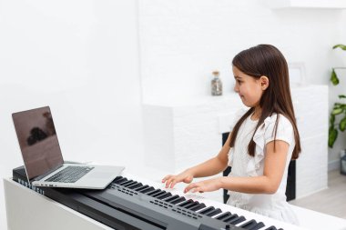 Evde online derste klasik dijital piyano çalan genç bir müzisyen, karantina sırasında sosyal mesafe, kişisel izolasyon, online eğitim konsepti