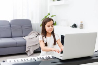 Evde online derste klasik dijital piyano çalan genç bir müzisyen, karantina sırasında sosyal mesafe, kişisel izolasyon, online eğitim konsepti