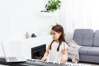 Evde online derste klasik dijital piyano çalan genç bir müzisyen, karantina sırasında sosyal mesafe, kişisel izolasyon, online eğitim konsepti