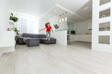 Uzun boylu, küçük bir kız çocuğu evde oynaşıp eğleniyor. Eğlenceli aktiviteler, sportif sağlıklı yaşam tarzı konsepti.