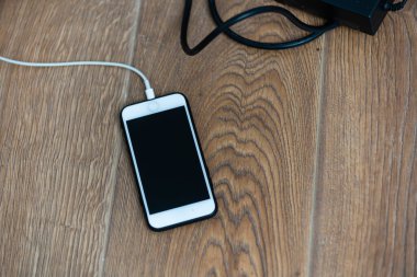 beyaz akıllı telefon uzantısı ahşap masa zemininde şarj olan cep telefonu sistemi