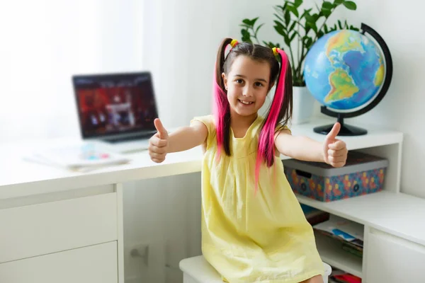 Cool online school. Kid studying online at home using a laptop. Cheerful young little girl using laptop computer studying through online e-learning system. Distance or remote learning
