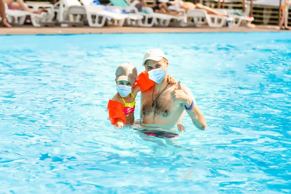 Vacation and technology. Happy familyin medical mask with kid together near swimming pool. Tourists fear the 2019-ncov virus. Medical masked tourists