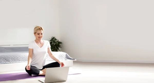 快乐的女人在家里一边做运动 一边看笔记本电脑上的运动视频 — 图库照片