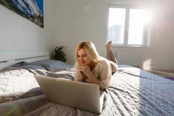 Usmívající Žena Ležící Posteli Před Svým Laptopem Lehce Zvednutýma Nohama — Stock fotografie