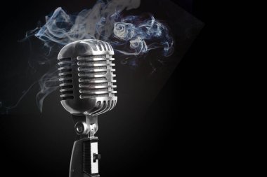 Bir mikrofonun etrafında müzik ya da eğlence konsepti için siyah arka planda duman vardır..