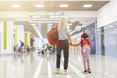 Anne ve çocuğun arka planda birlikte gitmesi. Alışveriş merkezi, havaalanı seyahati, aşk bakımı, koruma konsepti.