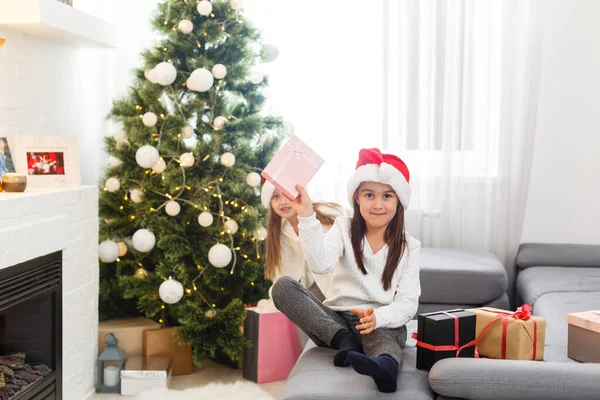 Дві Дівчинки Санта Капелюха Відкривають Різдвяний Подарунок Під Ялинкою — стокове фото