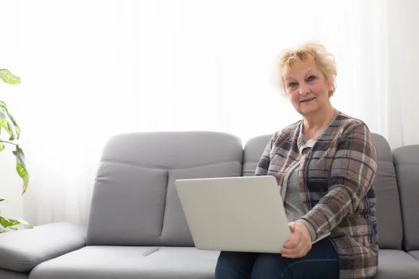 Пожилая Женщина Сидит Дома Используя Ноутбук Улыбаясь — стоковое фото