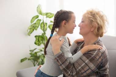 Küçük torunum ve mutlu büyükannem beşlik çakıyor kanepede birlikte oynayarak eğleniyorlar, büyükannem ve torunum evde iyi akrabaları kutlayarak gülüyorlar.