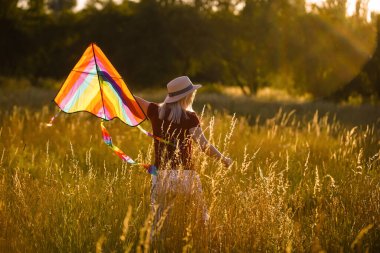 Yeşil alana uçurtma fırlatan genç ve kaygısız bir kadının portresi. Doğada aktif yaşam tarzı kavramı