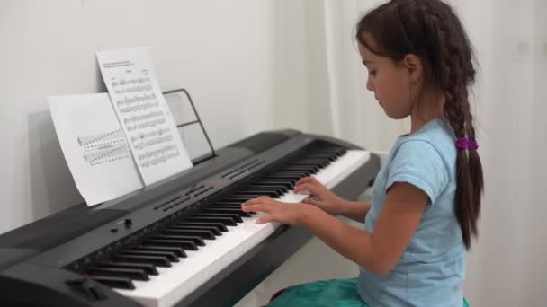 小女孩对着钢琴键盘笑 — 图库视频影像