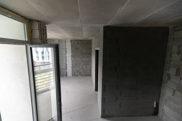 A new unfinished apartment room with the bare brick walls without decoration.