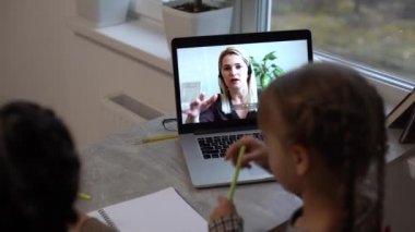 Mesafe öğrenme. Laptop 'ta Okul Kızları Maske Takıyor İnternette çalışıyor Evde masada oturuyor