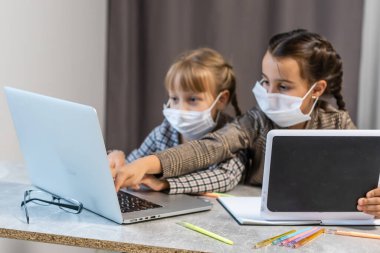 Yüz koruyucu maskeli genç liseli kızlar online eğitim sınıfını izliyorlar. Coronavirus veya Covid-19 tecrit eğitim kavramı.