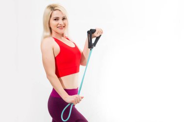 Kendine güvenen genç bir fitness kadınının portresi. Gri arka planda el açıcı ile egzersiz yapıyor.