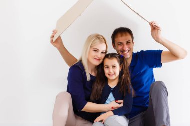 Aile bir arada oturuyor ve ev tabelasını yapıyor. Koronavirüslü normal bir hayat. Yaşam tarzı COVID-19. Karantina Virüsü Koruma Kısırlık Evi Kalp sembolü