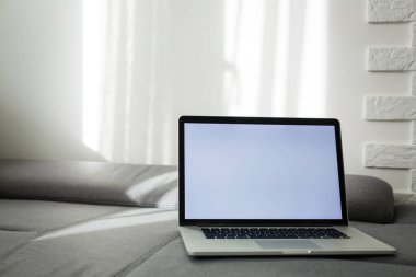 Kanepede dizüstü bilgisayarı aç. Modern konforlu iş yeri, mesafe çalışması. Metin için boş yer, kopyalama alanı.