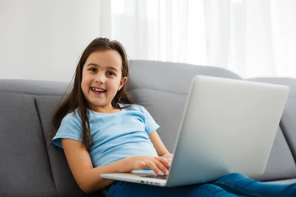 头部近距离拍摄了快乐的小学生在家中学习的肖像 笑着的小女孩喜欢在客厅里上课 聪明的女学生看着相机 在网上远程学习 — 图库照片