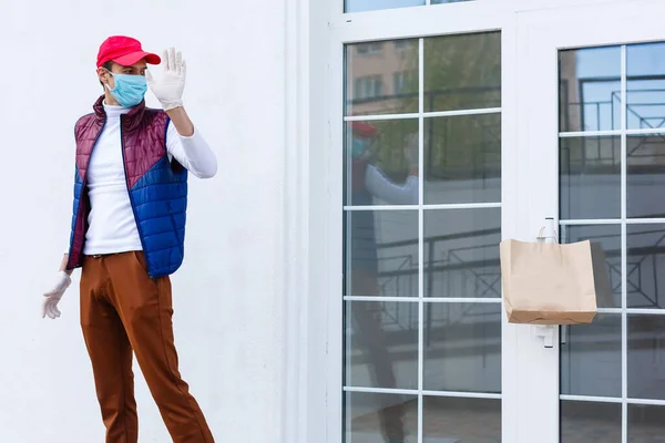 Grocery delivery man wearing medical gloves and face mask. Online shopping and delivery for grocerys, wine and food. Self Quarantine during coronavirus pandemic. Food delivery service courier