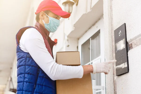 Kurye, tıbbi lateks eldivenli ve maskeli kurye Coronavirus salgını sırasında, COVID-19 'da beyaz kutuda güvenli bir şekilde online alışverişi teslim ediyor. Evde kal, güvenli konsept..
