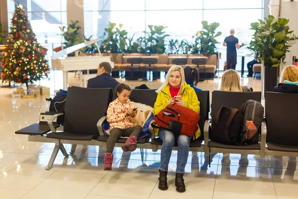 Адекватная девочка и ее мама ждут в аэропорту с багажом, путешествуют с детьми, семейный отдых, время в зале ожидания — стоковое фото