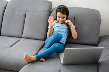 ev, eğlence, teknoloji ve internet konsepti - evde dizüstü bilgisayarı olan küçük kız öğrenci