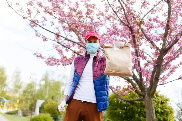 Grocery delivery man wearing medical gloves and face mask. Online shopping and delivery for grocerys, wine and food. Self Quarantine during coronavirus pandemic. Food delivery service courier