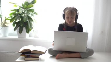 Evde bilgisayarını kullanarak internetten ders çalışan küçük bir kız.